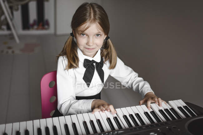 Retrato de uma menina sorridente tocando sintetizador — Fotografia de Stock