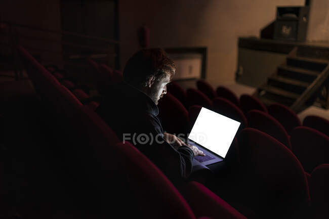 Direttore seduto all'auditorium di teatro che lavora su computer portatile — Foto stock