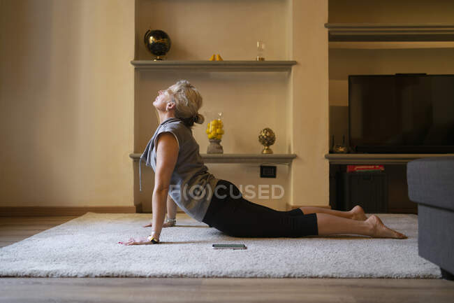 Mujer madura haciendo ejercicio de Yoga en el salón - foto de stock