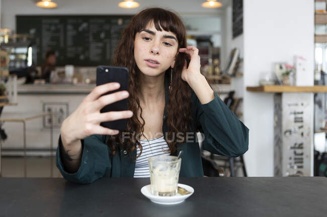 Jeune femme utilisant un téléphone portable dans un café — Photo de stock