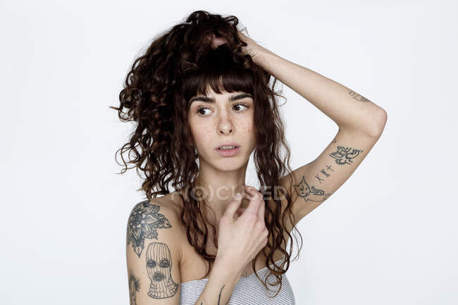 Retrato de mujer joven tatuada con la mano en el pelo - foto de stock