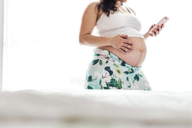 Mid-section of pregnant woman holding cell phone — Stock Photo
