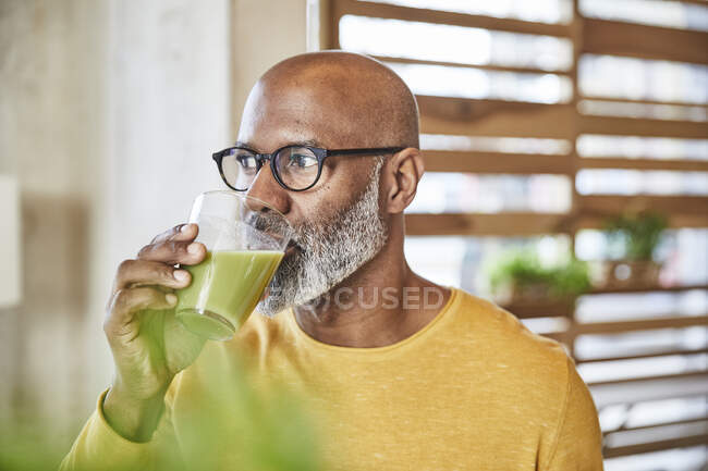Mature businessman in office drinking a smoothie — Stock Photo