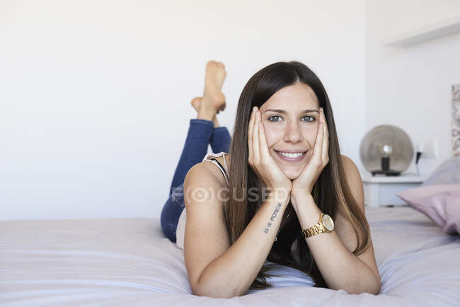 Ritratto di giovane donna sorridente sdraiata sul letto rilassante — Foto stock