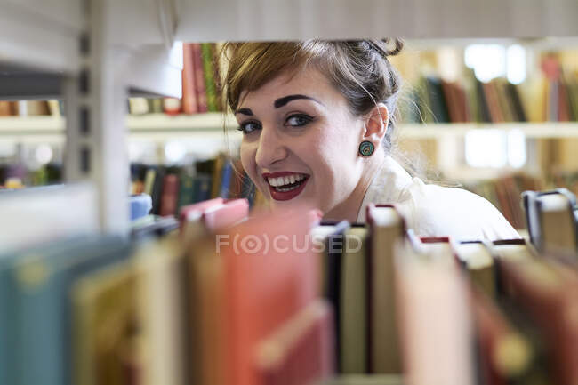 Female student reading book in a public library — Stock Photo