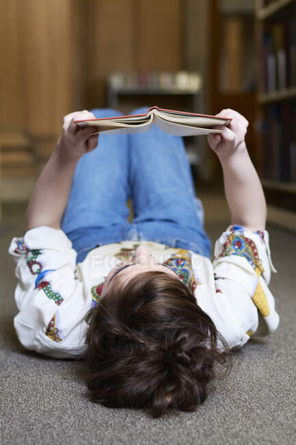 Une étudiante lit un livre dans une bibliothèque publique — Photo de stock