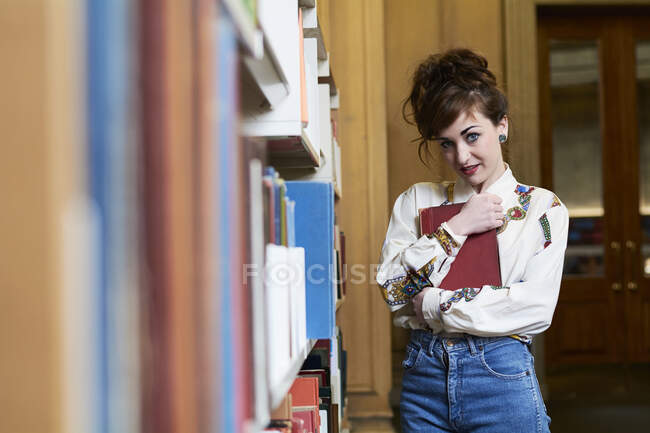 Студентка тримає книжку в публічній бібліотеці. — стокове фото