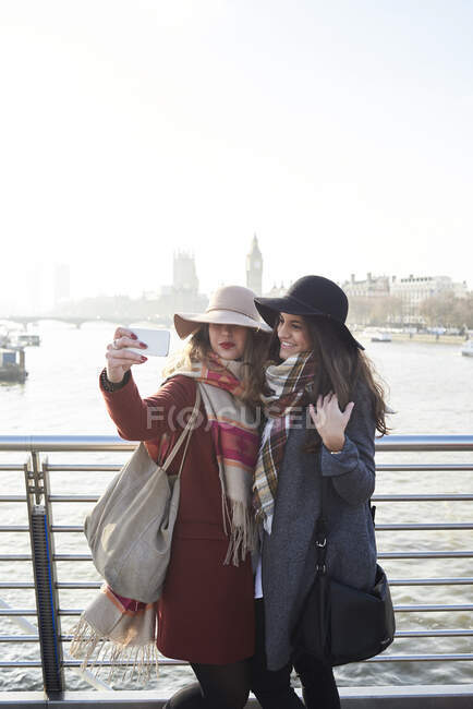 Regno Unito, Londra, due donne scattano un selfie sul Millennium Bridge con paesaggio urbano sullo sfondo — Foto stock