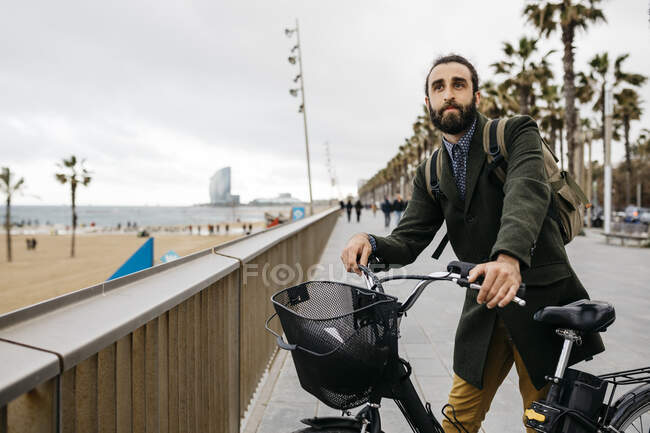 Man with e-bike having a break on beach promenade — Stock Photo