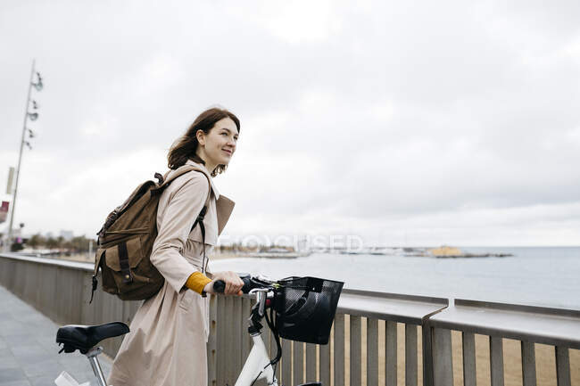 Lächelnde Frau mit E-Bike macht Pause an der Strandpromenade — Stockfoto