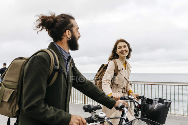 Lächelndes Paar mit E-Bikes auf Strandpromenade — Stockfoto