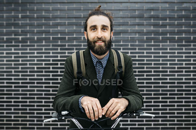 Portrait d'homme souriant avec e-bike à un mur de briques — Photo de stock