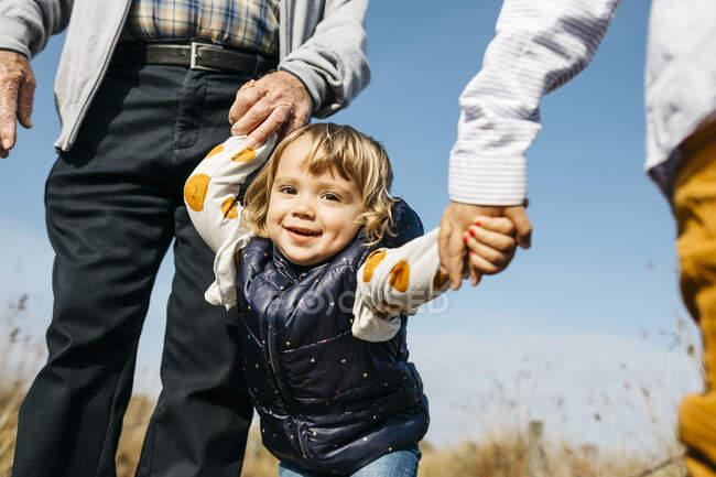 Porträt eines glücklichen kleinen Mädchens, das Hand in Hand mit Großvater und Bruder in der Natur spaziert — Stockfoto