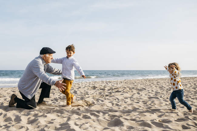 Nonno che gioca con i nipoti in spiaggia in primavera — Foto stock