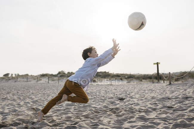 Маленький хлопчик грає у футбол на пляжі — стокове фото