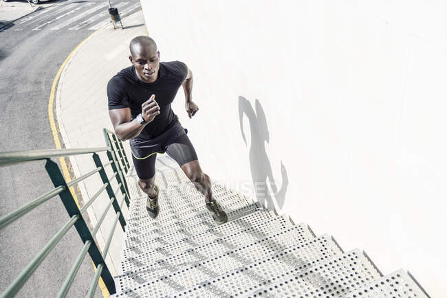 Man in black sportswear running up staircase — Stock Photo