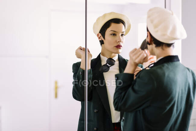 Jeune femme à la mode vérifiant son regard dans le miroir — Photo de stock