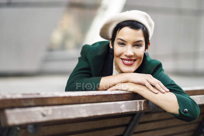 Портрет усміхненої модної молодої жінки, що сидить на лавці — стокове фото