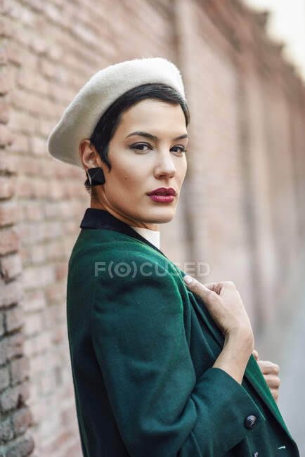 Retrato de mulher jovem na moda em uma parede de tijolo — Fotografia de Stock