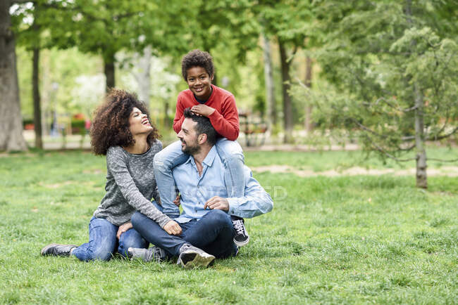 Счастливая семья сидит на траве в парке — стоковое фото