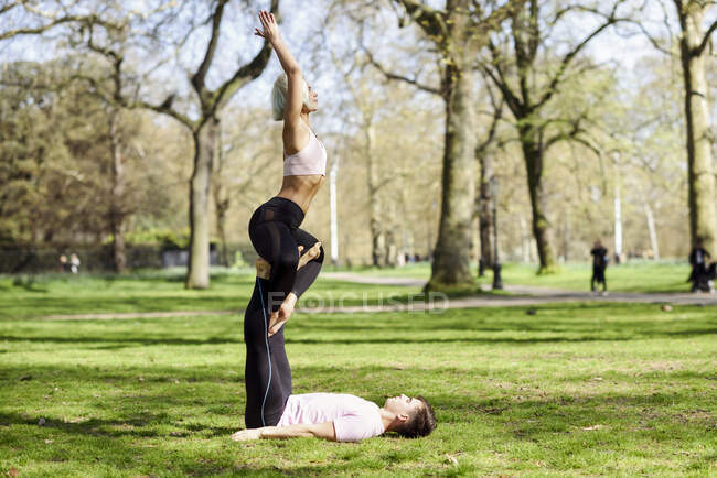 Pareja joven haciendo acrobacias de yoga en un parque urbano - foto de stock