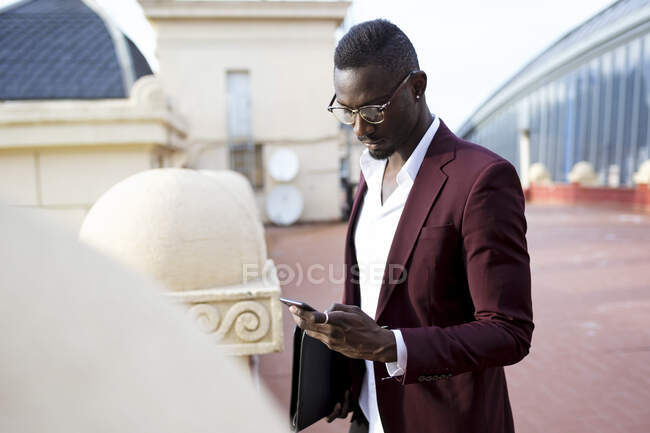 Young entrepreneur wating on hotel terrace for his appointment, using smartphone — Stock Photo