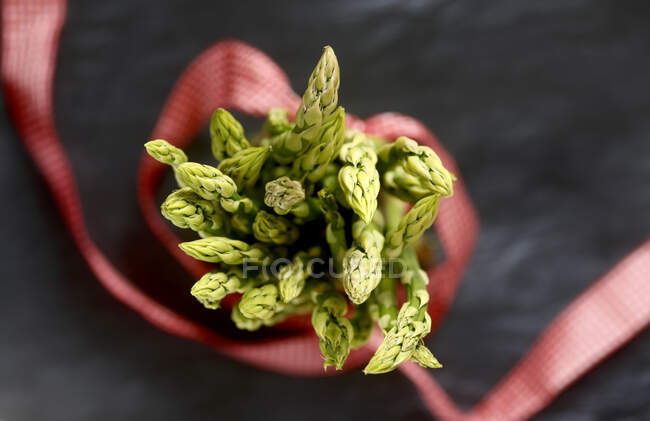 Green asparagus, red ribbon, close up — Stock Photo