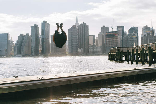 USA, New York, Brooklyn, giovani che fanno backflip sul molo di fronte allo skyline di Manhattan — Foto stock