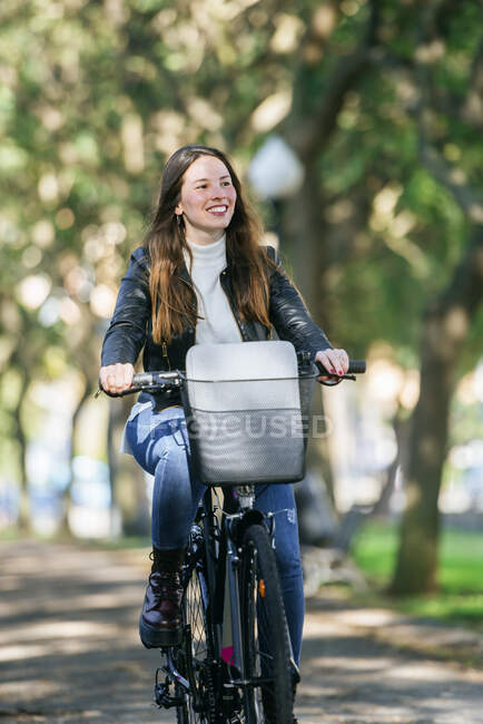 Souriant jeune femme à vélo dans le parc — Photo de stock