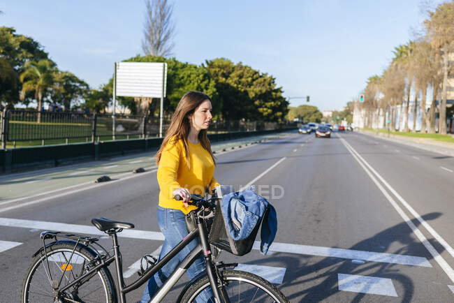 Junge Frau überquert mit Fahrrad die Straße — Stockfoto