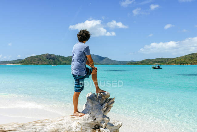 Australia, Queensland, Whitsunday Island, man standing on log at Whitehaven Beach — Fotografia de Stock
