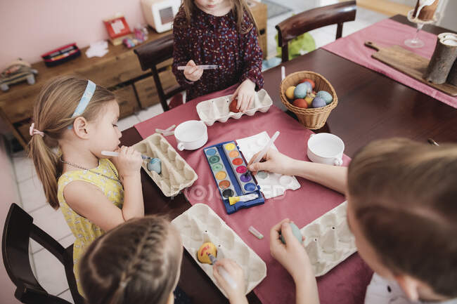 Children painting Easter eggs on table at home — Stock Photo