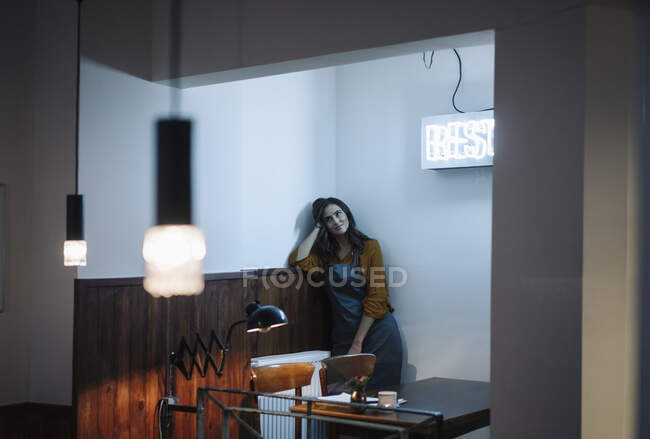 Young woman leaning against a wall under neon light — Stock Photo