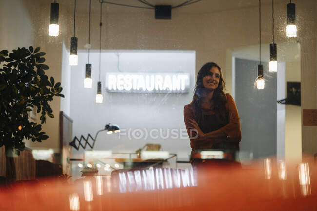 Donna sorridente che indossa grembiule in piedi in un ristorante — Foto stock