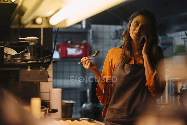 Jeune femme parlant sur téléphone portable dans la cuisine du restaurant — Photo de stock