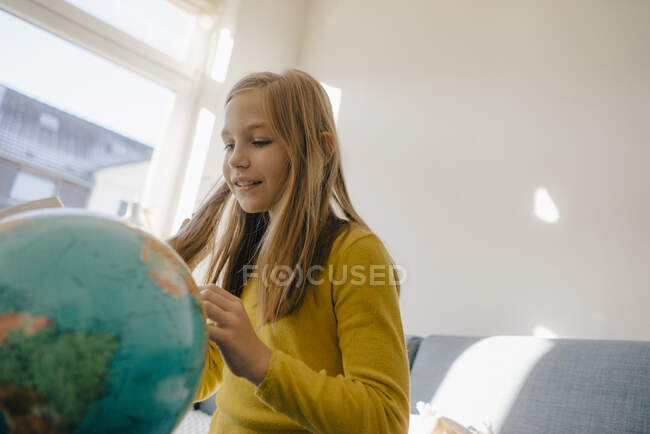 Girl at home looking at globe — Stock Photo