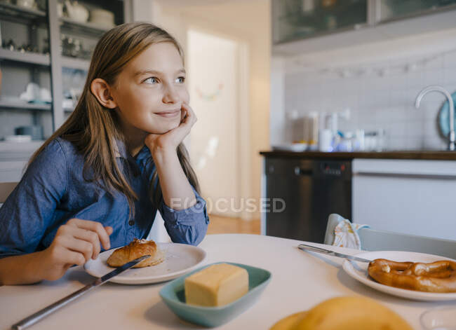 Souriante fille à la maison assise à la table du petit déjeuner — Photo de stock