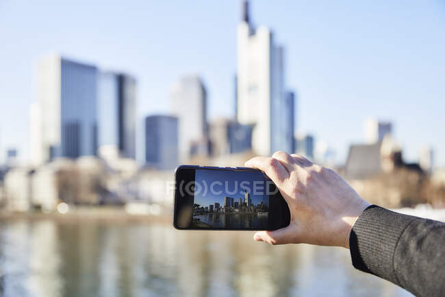 Germany, Frankfurt, hand taking photo of financial district with cell phone — Stock Photo