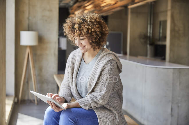 Mujer sonriente usando la tableta en la oficina moderna - foto de stock