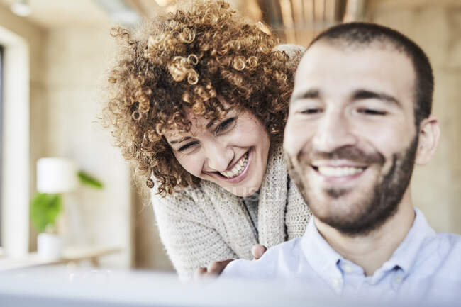 Щасливий чоловік і жінка, які поділяють таблетку в сучасному офісі. — стокове фото