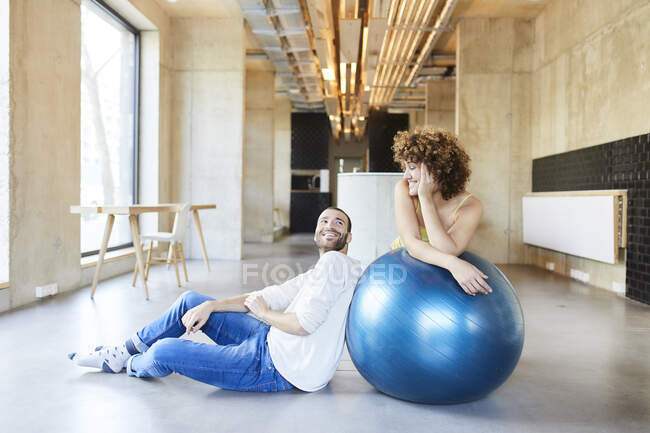 Homme et femme souriants avec balle de fitness dans le bureau moderne — Photo de stock