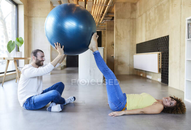 Счастливые мужчина и женщина практикуют с фитнес-мяч в современном офисе — стоковое фото
