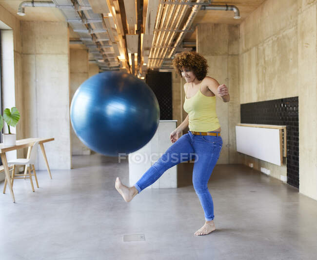 Женщина снимает фитнес-мяч в современном офисе — стоковое фото