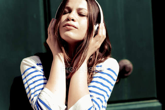 Молода жінка слухає музику з закритими очима. — стокове фото