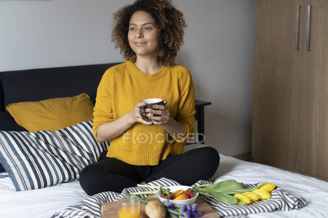 Mujer sentada en la cama, desayunando sano - foto de stock