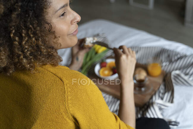 Woman sitting on bed, having a healthy breakfast — Stock Photo