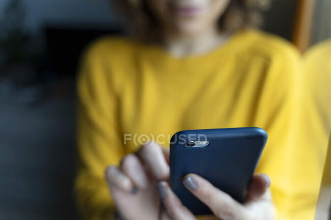 Женщина в желтом пуловере, с помощью смартфона — стоковое фото