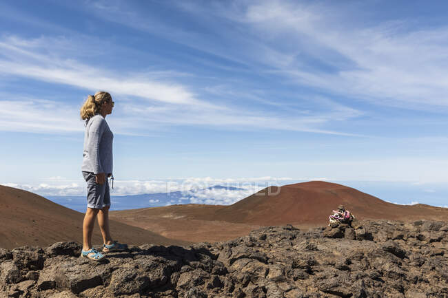 EEUU, Hawái, volcán Mauna Kea, turista femenina mirando al paisaje volcánico - foto de stock