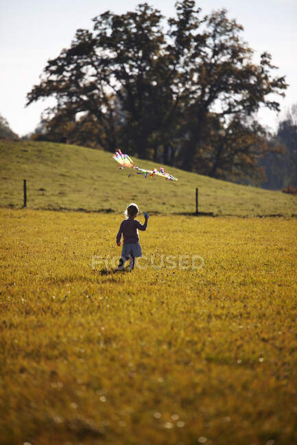 Bambina in piedi in campo con aquilone — Foto stock