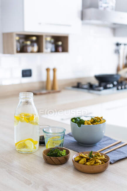 Curry chicken, broccoli and rice with a bottle of infused water — Stock Photo
